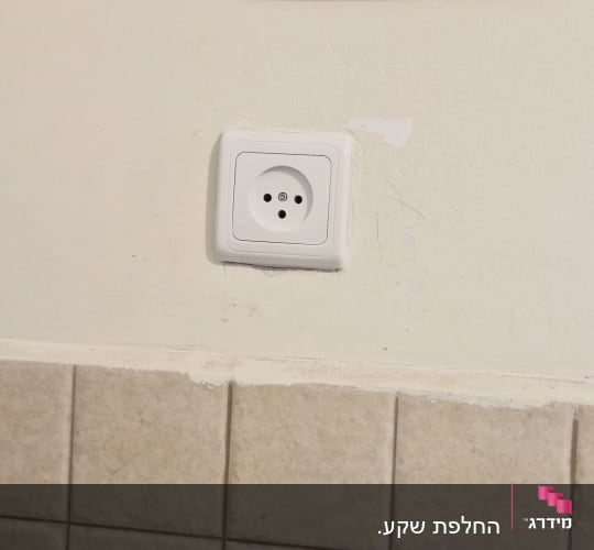 שקע חשמלי מותקן על קיר עם אריחים
